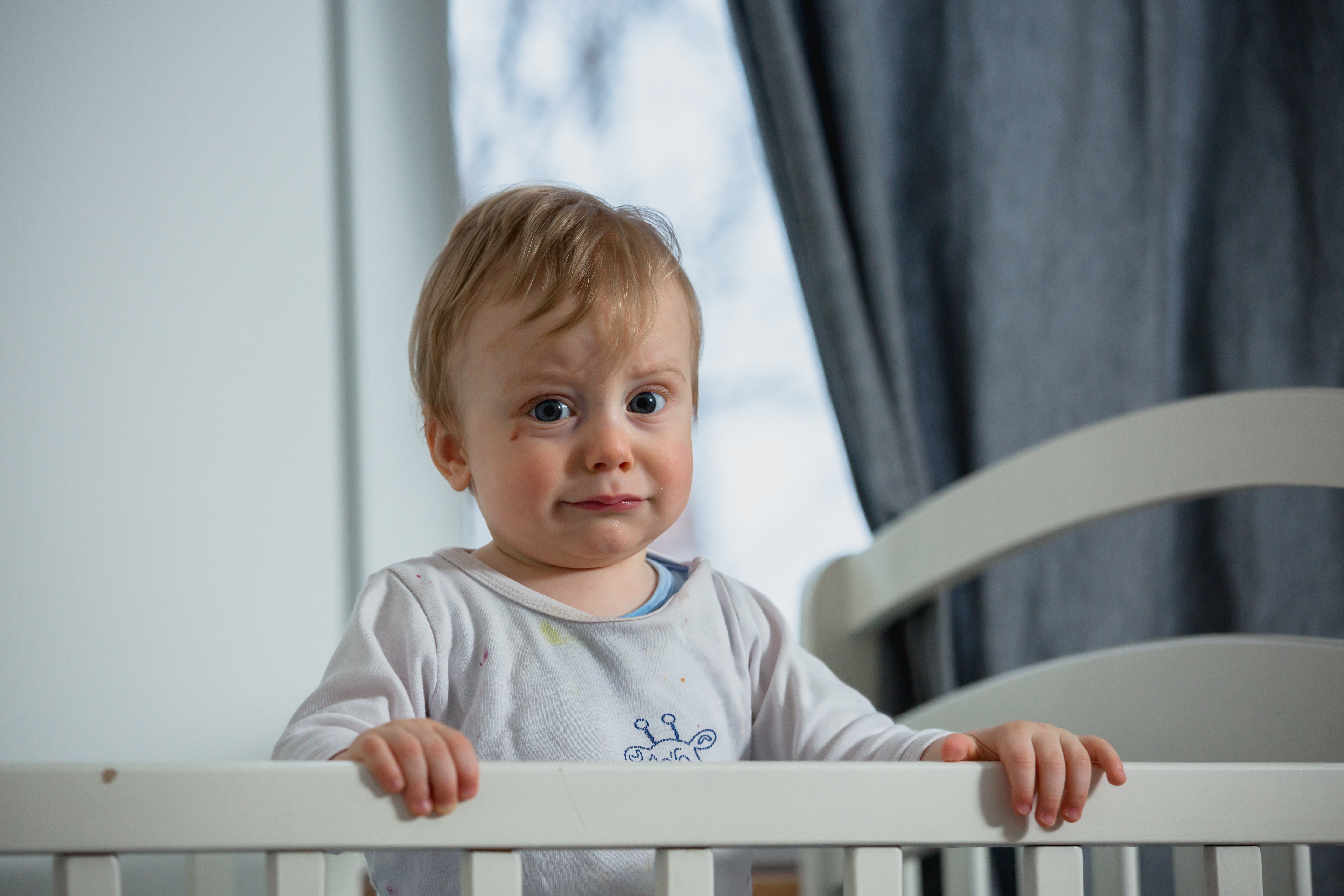 sad-baby-boy-standing-in-cot.jpeg