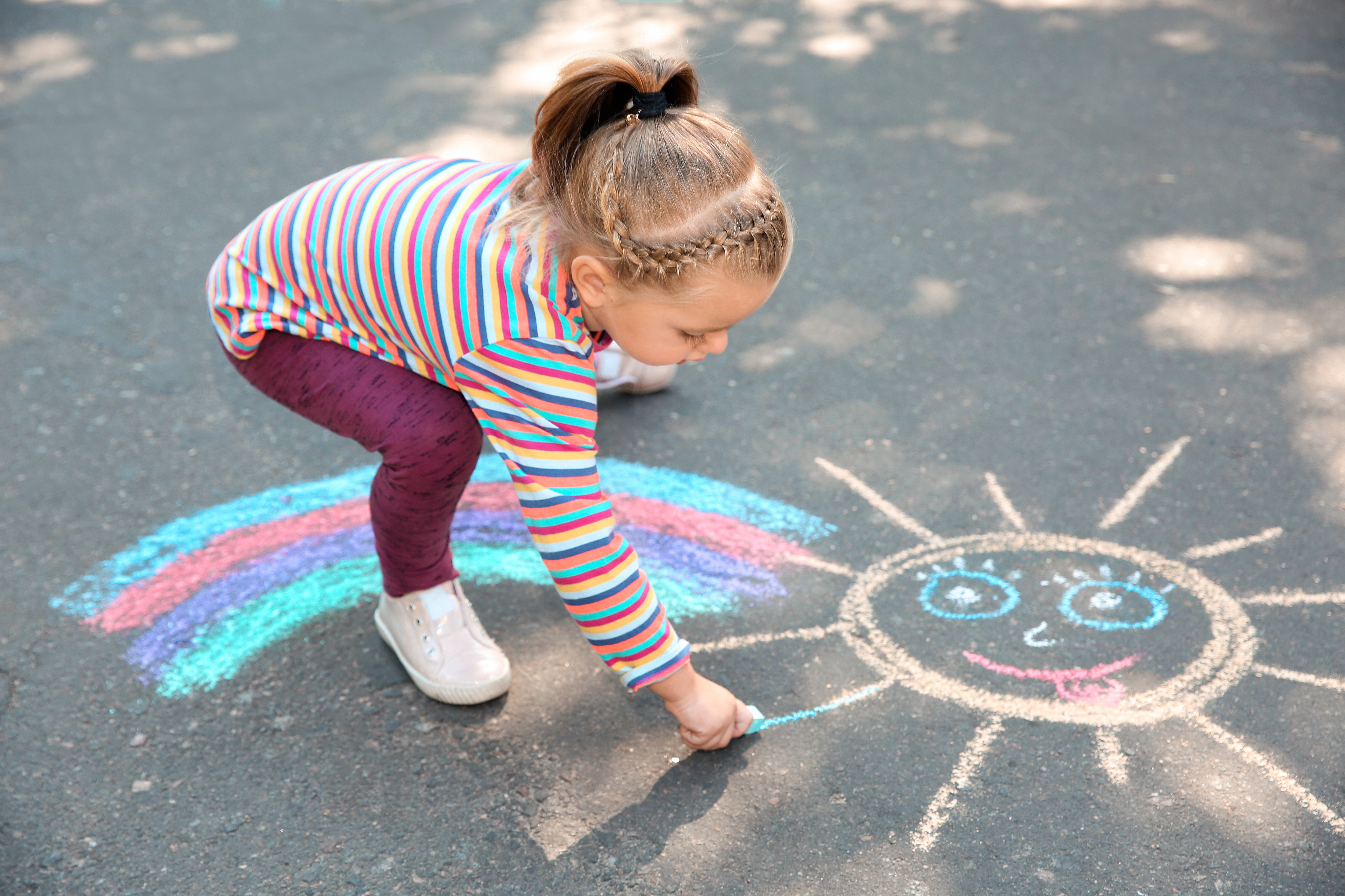 girl-drawing-chalk-rainbow-in-playground.jpeg